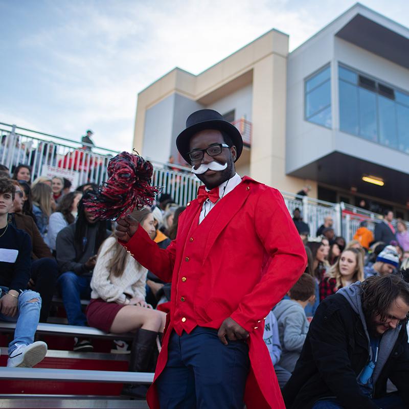 Student dressed as gov poses for photo in football stadium